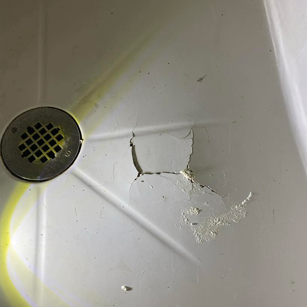 Base de bain en acrylique fissurée et écaillée, avec marques d’usure visibles avant réparation.